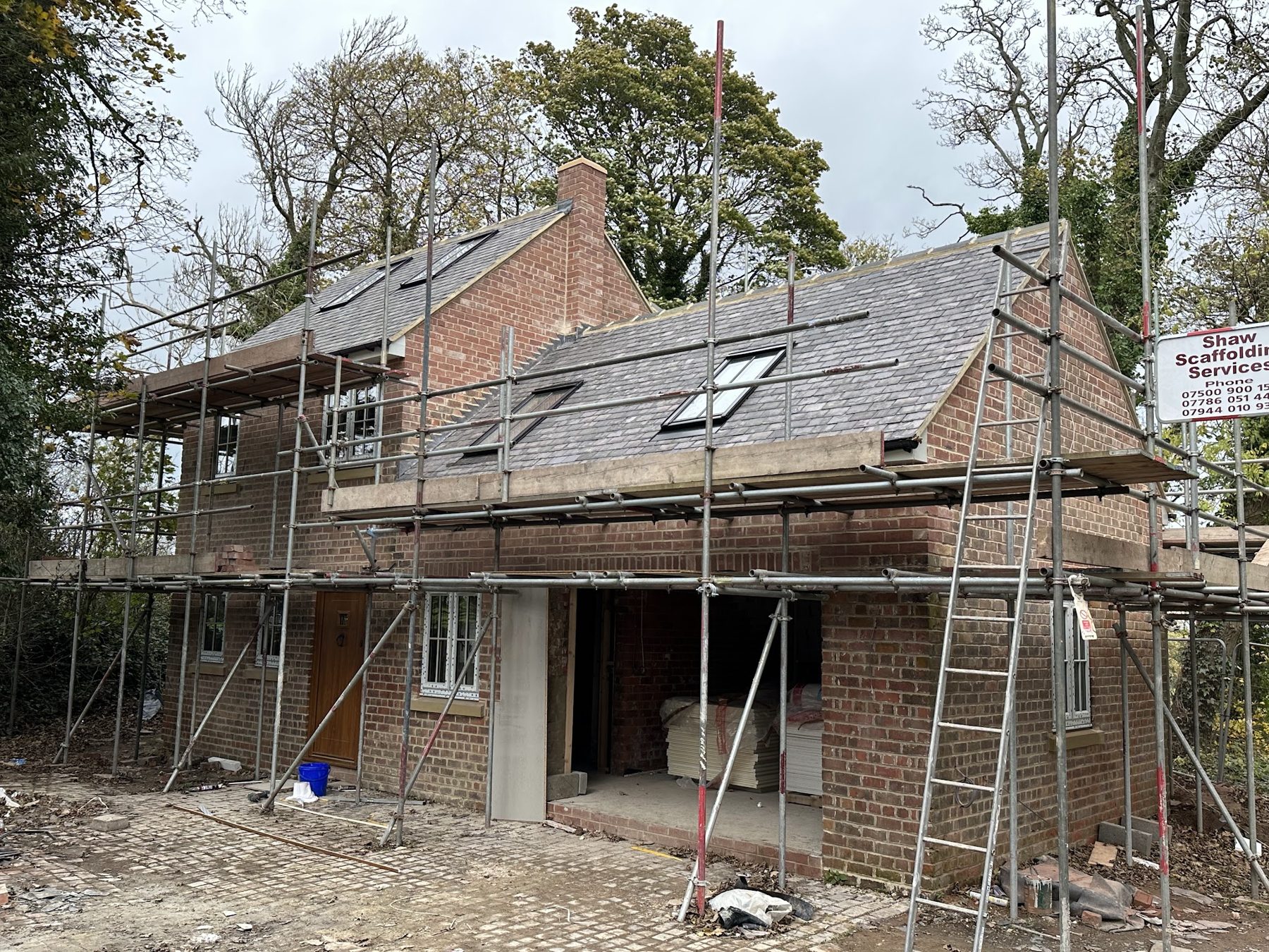 A two-storey brick house under scaffold with the roof on