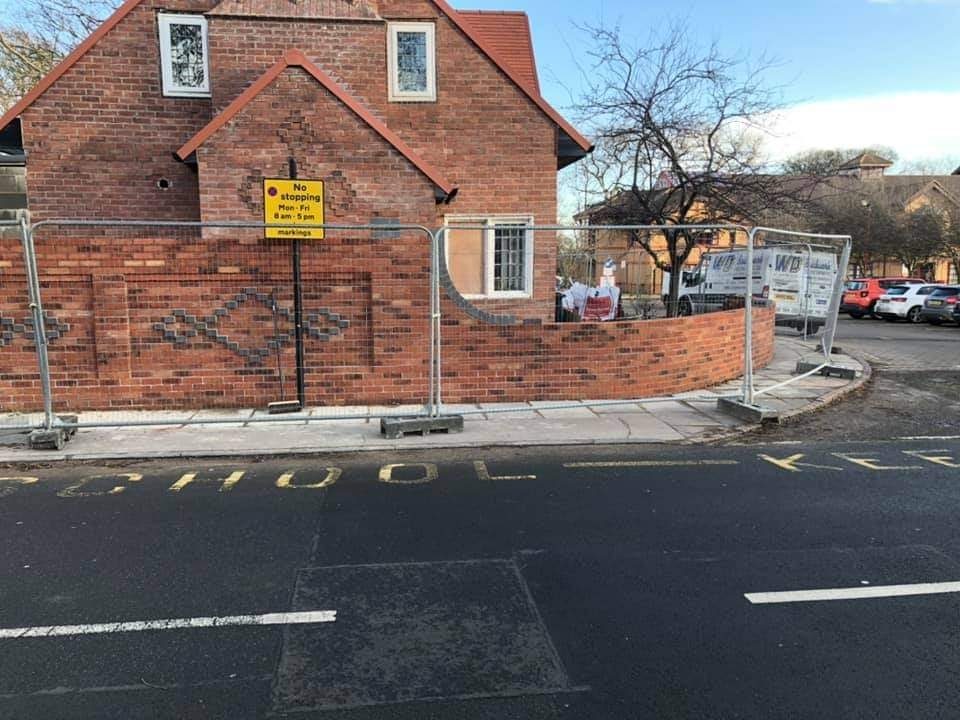 A corner boundary wall with a diamond pattern laid in darker bricks