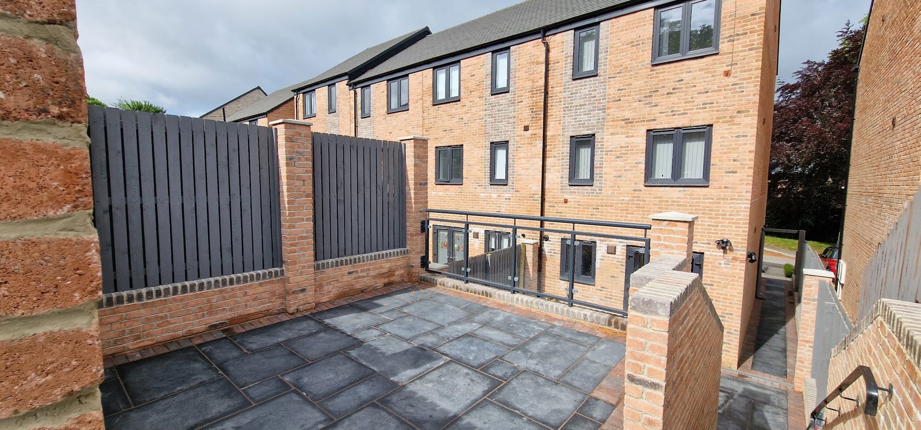 Brick piers with slatted fence panels around a paved courtyard