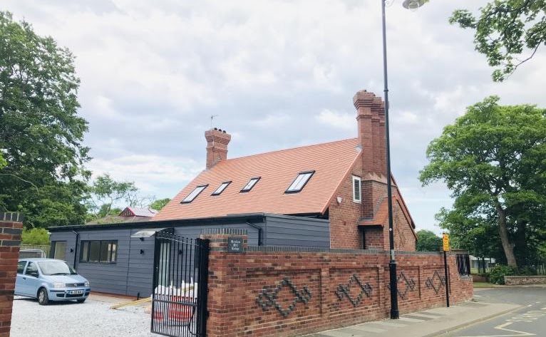 A finished detached house with a patterned brick boundary wall and gates