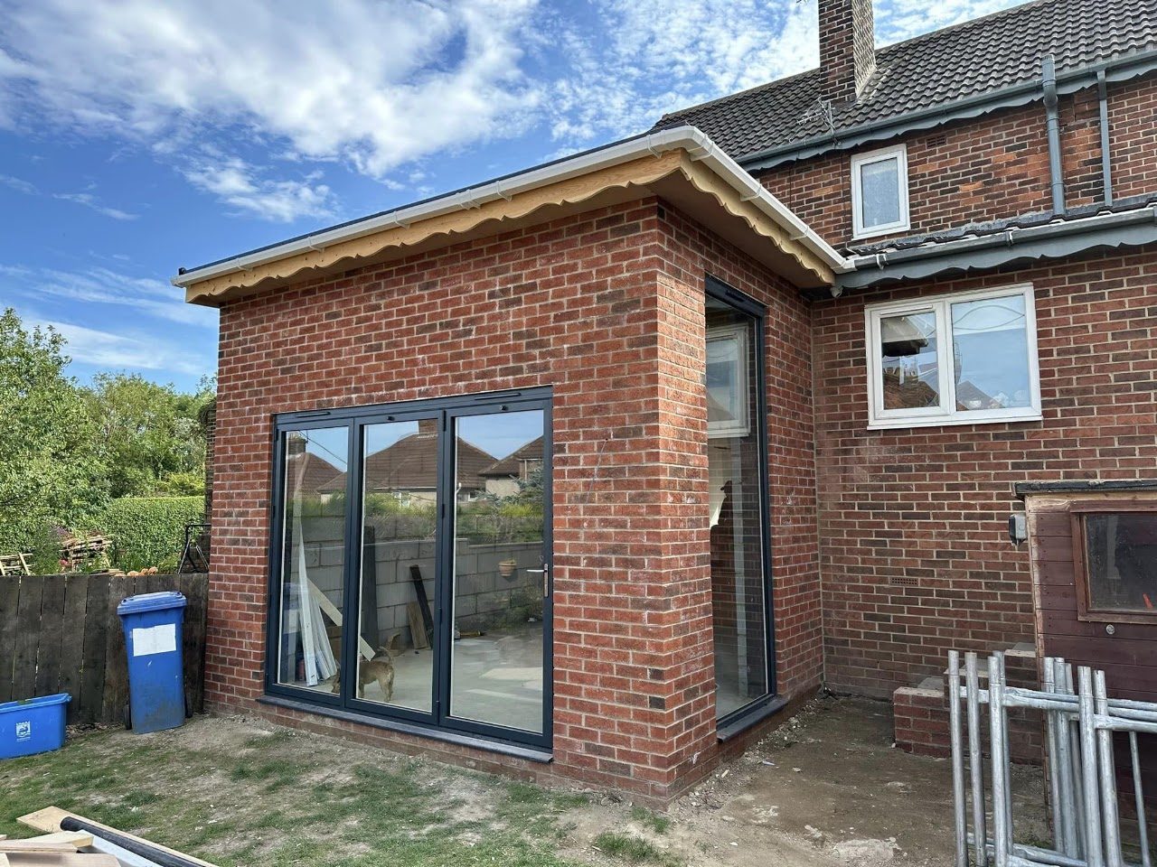 A single-storey red brick extension with grey bifold doors