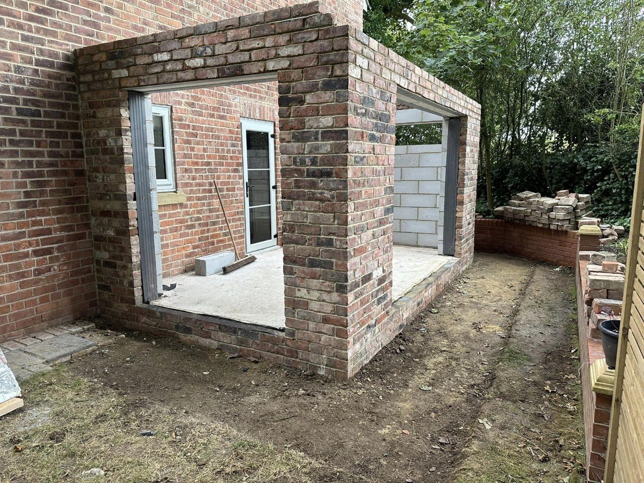 The brick shell of an extension with door openings formed