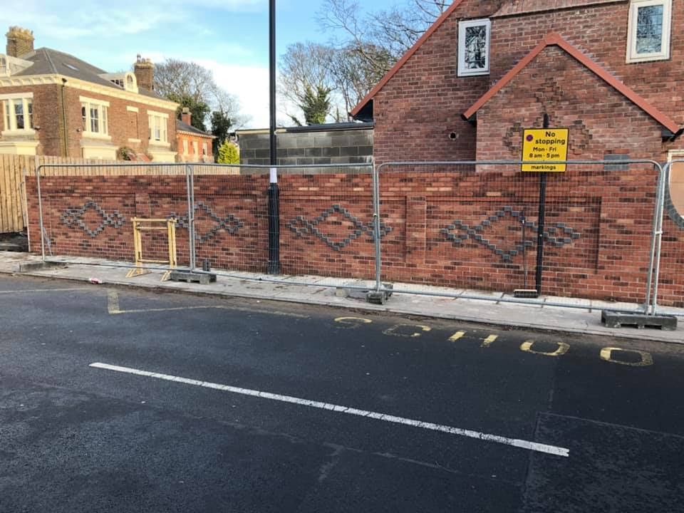 A new red brick boundary wall with a diamond pattern in darker bricks